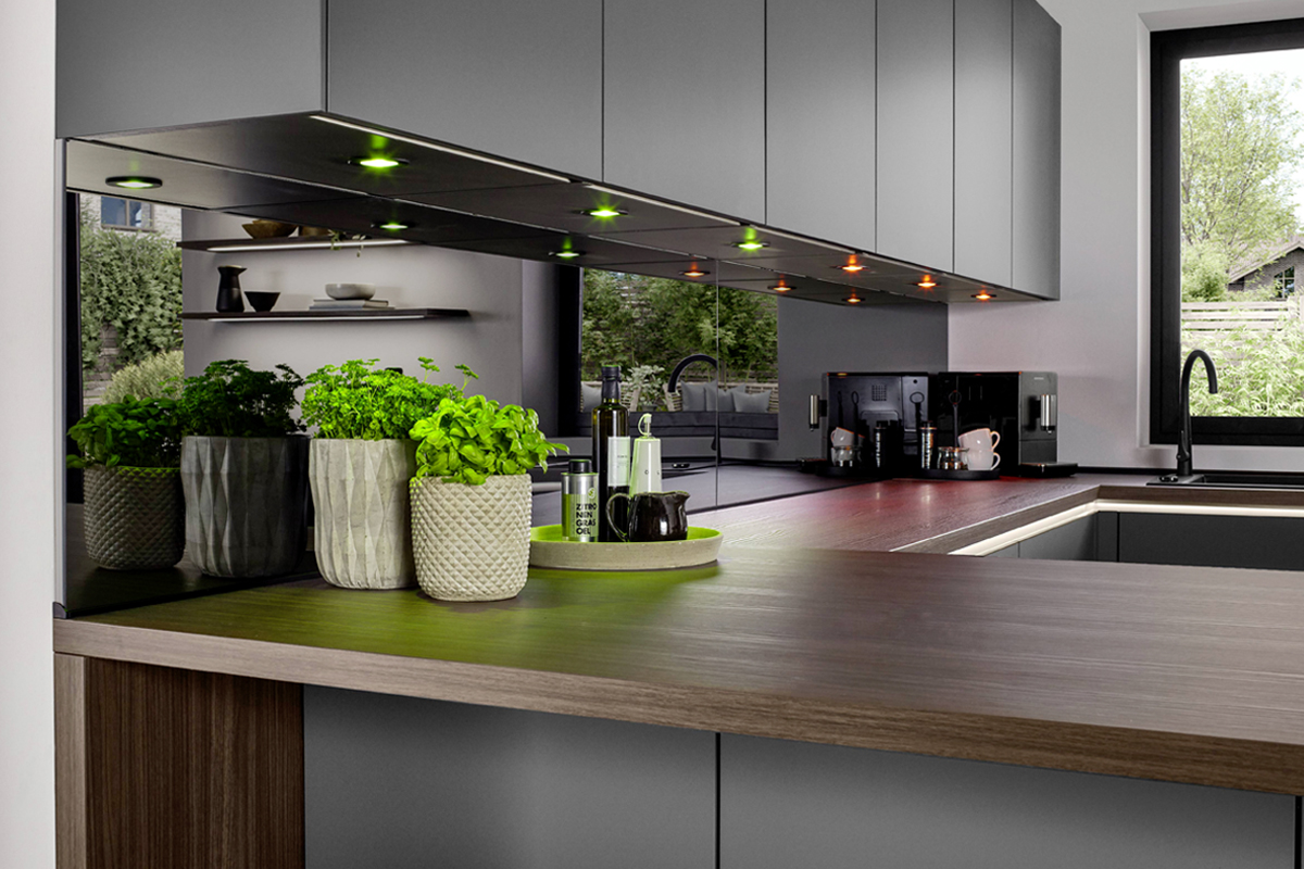 Geschmackvolle Atmosphäre! Die edle Arbeitsplatte in Nussbaumoptik setzt einen warmen Akzent zum Schiefergrau und schafft ein angenehmes Ambiente. Fur die passende Lichtstimmung sorgen die Philips Hue Einbaustrahler, die smart zwischen Arbeitslicht und Wohnlichkeit wechseln.